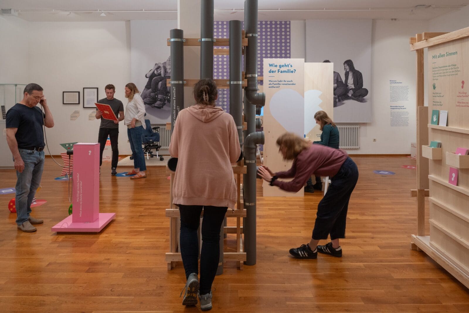 Sechs Personen im Ausstellungsraum, die verschiedenen Stationen ausprobieren.